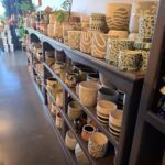 A large collection of vases and cups are displayed on a shelf.