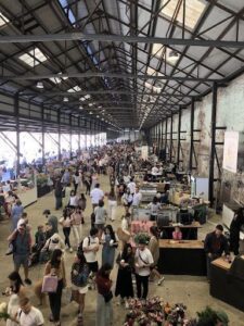 A large crowd of people are walking through a building, likely a market or a shopping area.