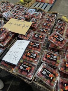 A large display of strawberries for sale, with a sign indicating a special offer.