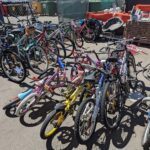 A large group of bikes are parked together, some with baskets attached.