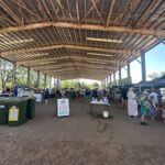 A large group of people are gathered in a marketplace, shopping and socializing.
