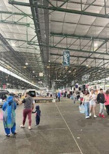A large group of people are walking around a building, possibly shopping or attending an event.