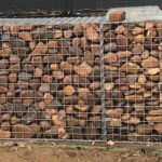 A large pile of rocks is secured behind a wire fence.