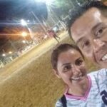A man and a woman are posing for a picture on a soccer field.