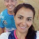 A man and woman pose for a picture in front of a soccer goal.
