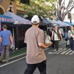 A man in a white hat is walking down a street with a box in his hand.