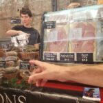 A man is pointing at a price sign for ham.