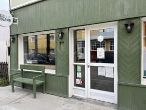 A man is sitting in a car in front of a green building.