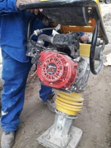 A man is working on a red and black engine, possibly a Honda.