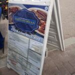A menu sign for a restaurant is displayed on a sidewalk.