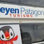A penguin is shown in front of a sign for a tour company.