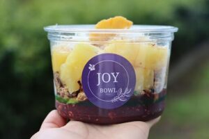 A person is holding a bowl of food with the words "joy" and "bowl" on it.