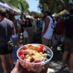 A person is holding a bowl of fruit in front of a crowd of people.