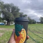 A person is holding a coffee cup with a woman's face on it.