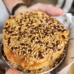 A person is holding a pastry with seeds on top.