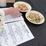 A person is holding a plate of food in front of a menu.