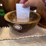 A person is holding a receipt for a wooden bowl.