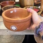 A person is holding a wooden bowl with a price tag on it.