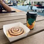 A person is sitting at a table with a cup of coffee and a pastry.