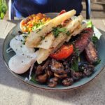 A plate of food with a sandwich, mushrooms, tomatoes, and eggs.