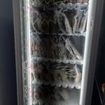 A refrigerator filled with various food items, including sandwiches, is displayed in a store.
