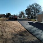 A road is being paved with a tractor and a backhoe.