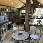 A rustic cabin with a piano, tables, and chairs.