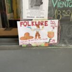 A sign advertising a Folklore event is posted on a wall.