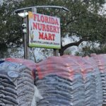 A sign for a nursery mart is displayed in front of a pile of bags.