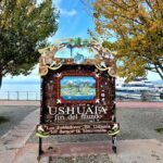A sign for Ushuaia is displayed in front of a tree.