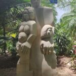 A statue of a woman and a child is located in a park.