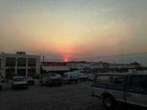 A sunset over a parking lot with cars and trucks parked.