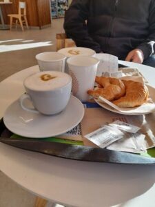 A table with a tray of food, including croissants and coffee.