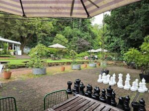 A table with chairs and a checkerboard set up in a park.