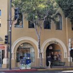 A tree in front of a building with a sign that says "Slo Swim".