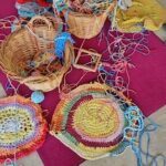A variety of colorful crocheted items are displayed on a pink surface.