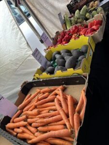 A variety of fresh vegetables are displayed for sale, including carrots and peppers.