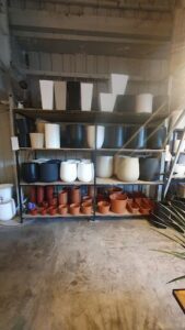 A variety of pots and vases are displayed on a shelf, showcasing different shapes and sizes.