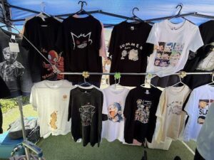 A variety of shirts are hanging on a rack, including a black shirt with a wolf on it.