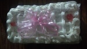 A white cake with a pink bow on top.