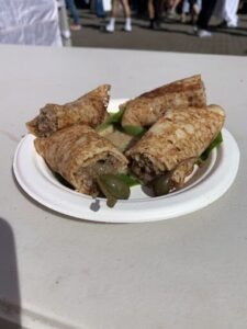 A white plate with a variety of food items, including a sandwich, a burger, and a pita bread.