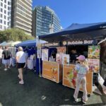A woman in a pink hat is standing in front of a food stand, ordering a drink.