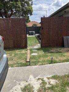 A wooden fence with a gate that leads to a backyard.