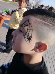 A young boy with spider web tattoos on his face.