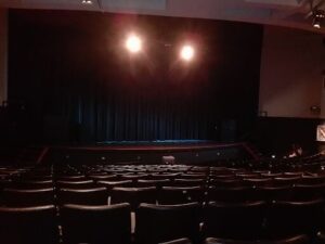 An empty auditorium with a stage and a blue curtain.