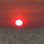 The sun is setting over the ocean, creating a beautiful orange glow.