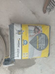 A bag of cement sits on a dirty floor.