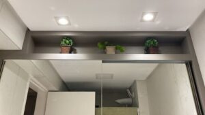 A bathroom with a mirror and three potted plants on the wall.
