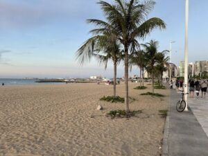 A beach scene with a bicycle parked on the sidewalk.