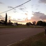 A beautiful sunset over a field with a person standing on the side of the road.
